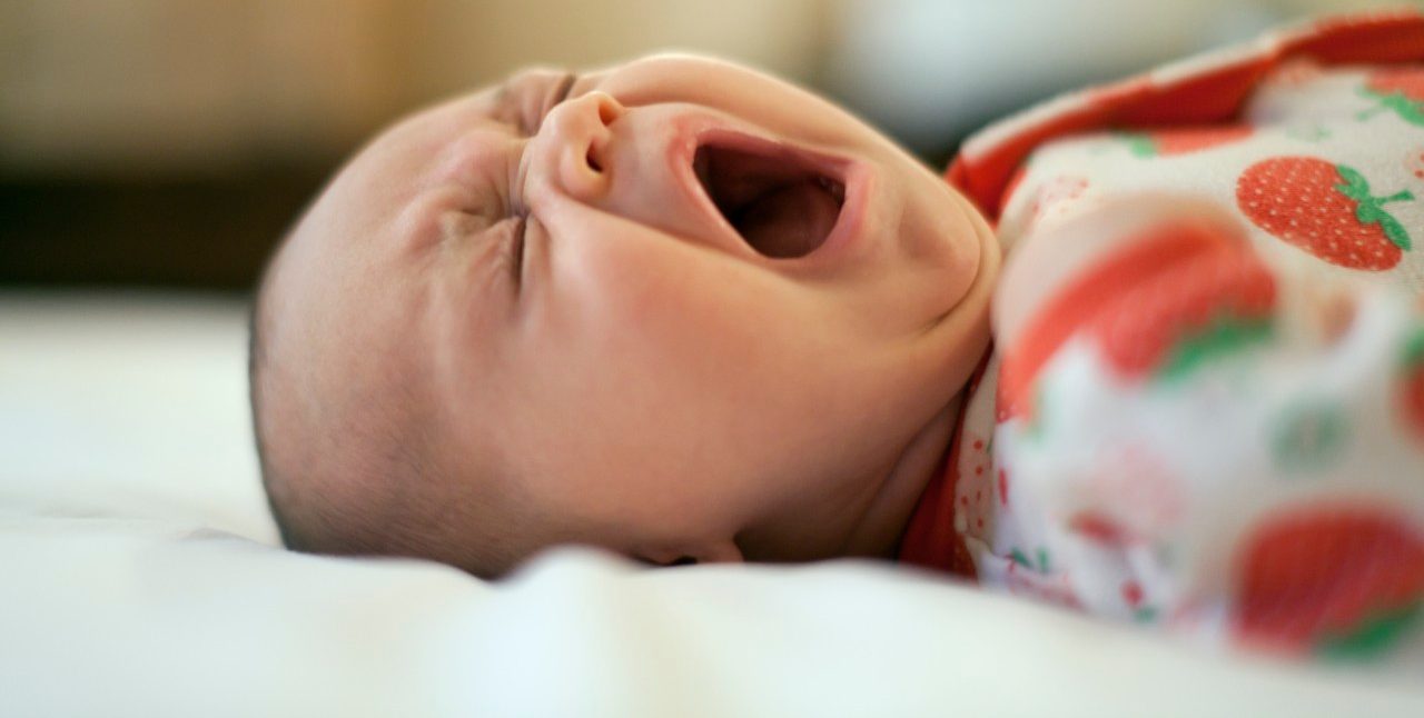 Two month old baby lying down yawning --- Image by © MKeal/Corbis