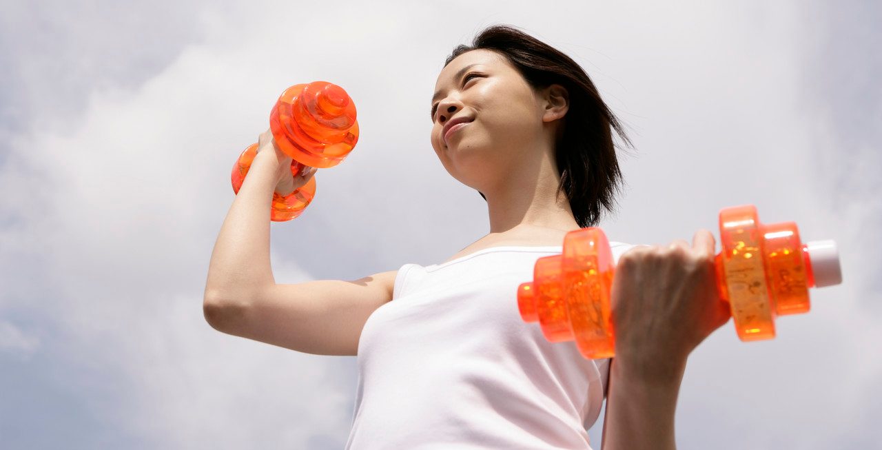 A woman exercising as she lifts up the dumbbells --- Image by © Image Werks/Corbis