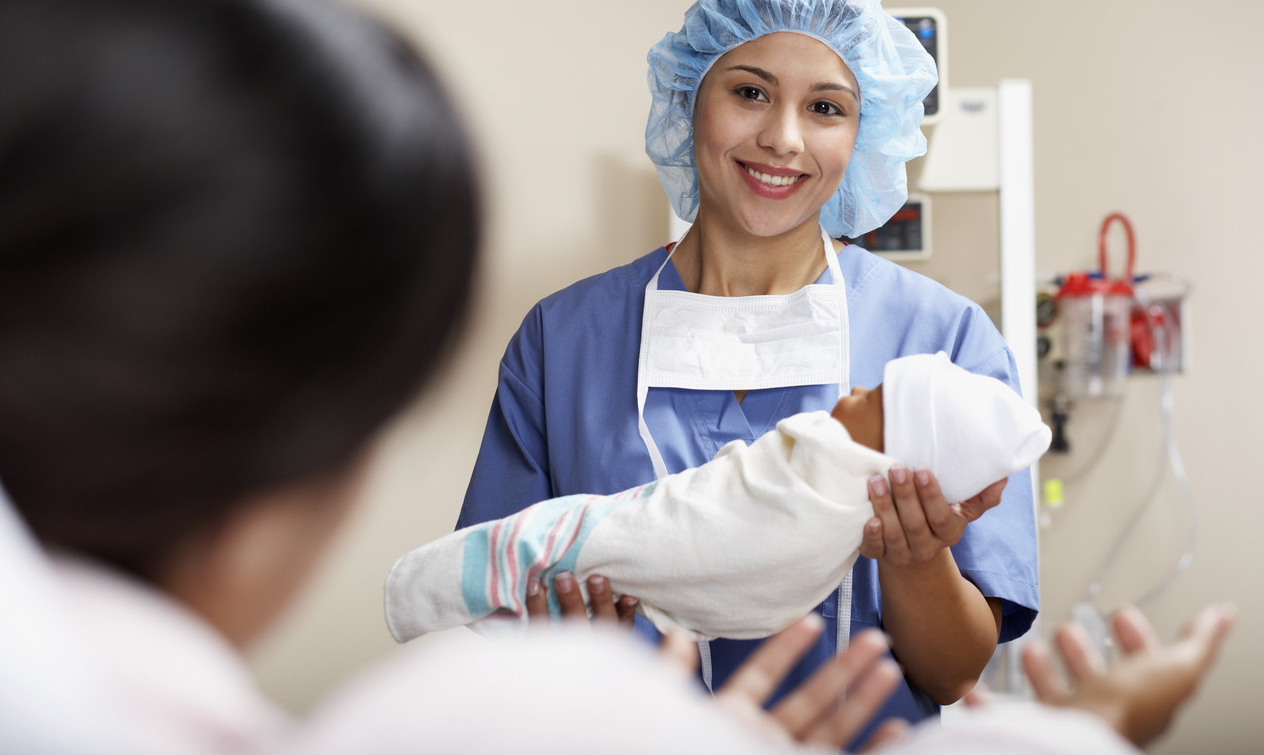 Physician Handing Newborn to Mother --- Image by © Jack Hollingsworth/Corbis