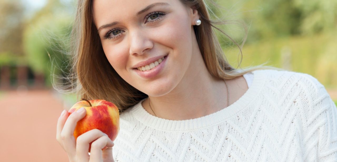 18 Oct 2014, Düsseldorf, Germany --- Portrait of smiling blond teenage girl eating an apple --- Image by © reka prod./Westend61/Corbis