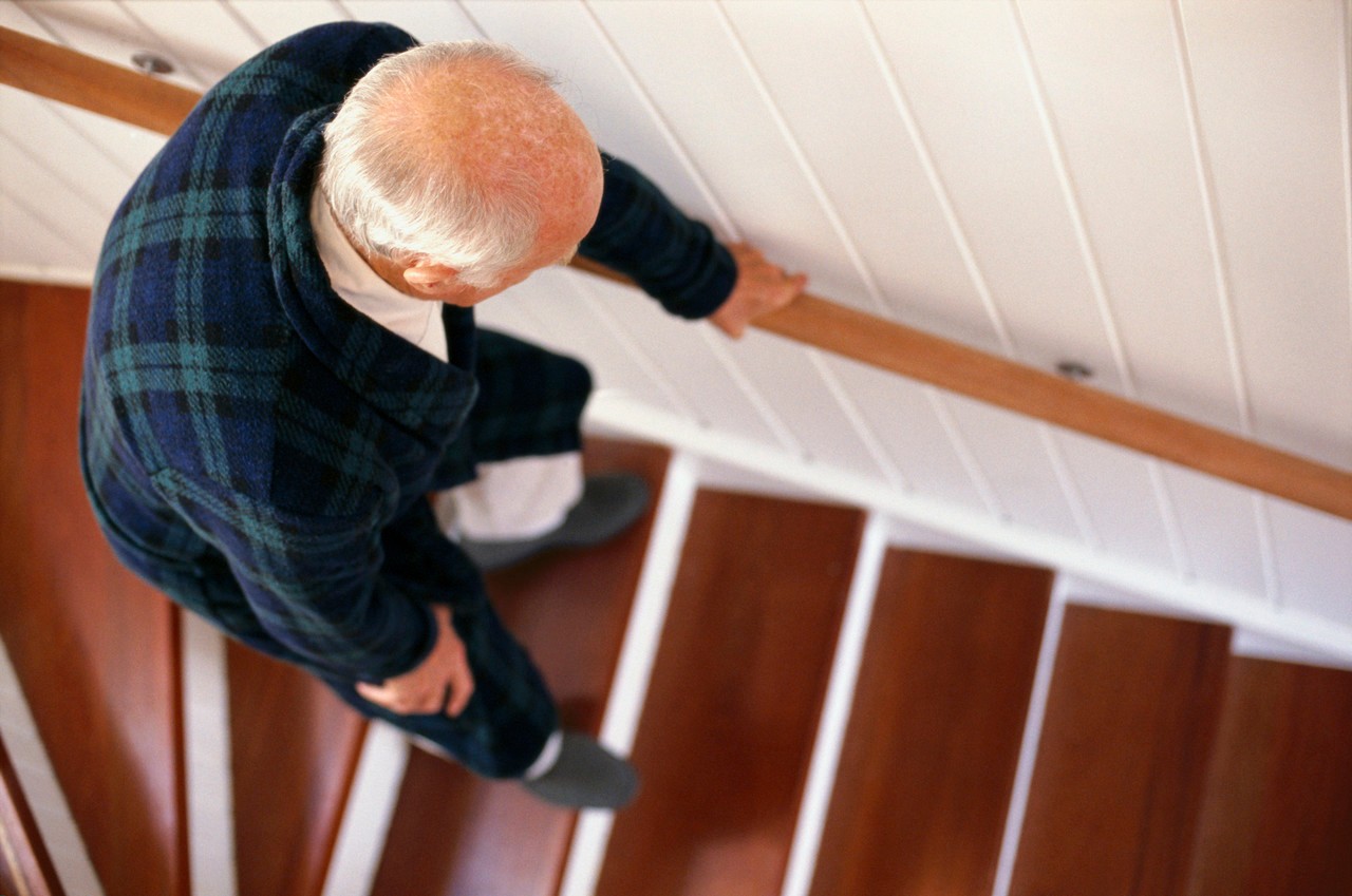 An elderly man carefully descends a staircase --- Image by © Whisson/Jordan/Corbis