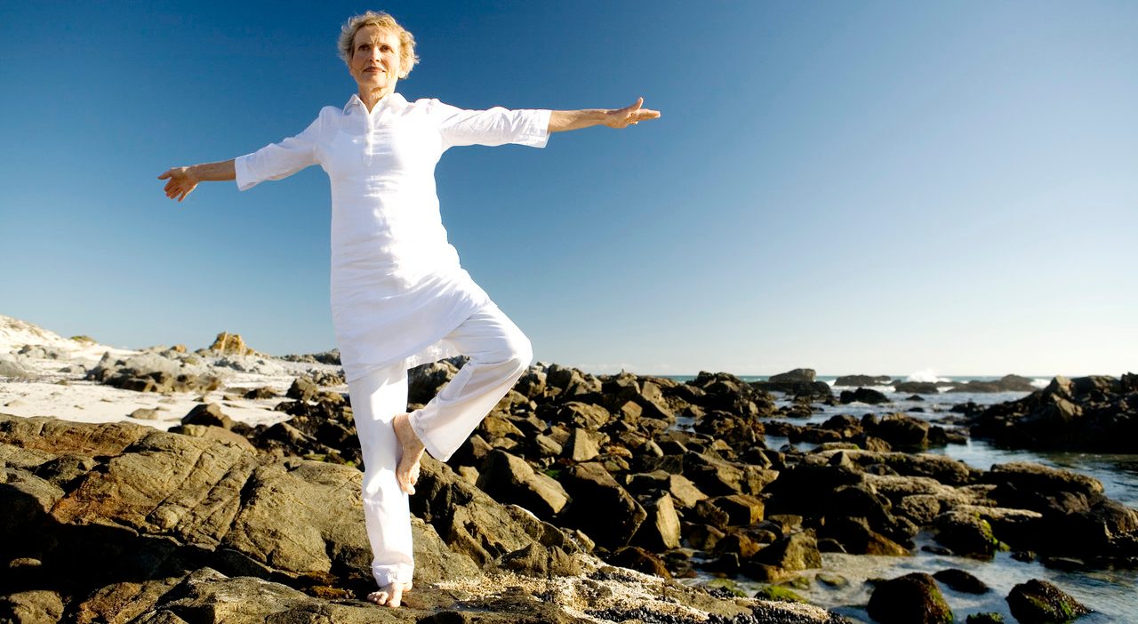 Senior woman doing yoga on seaside rocks --- Image by © Elie Bernager/Onoky/Corbis