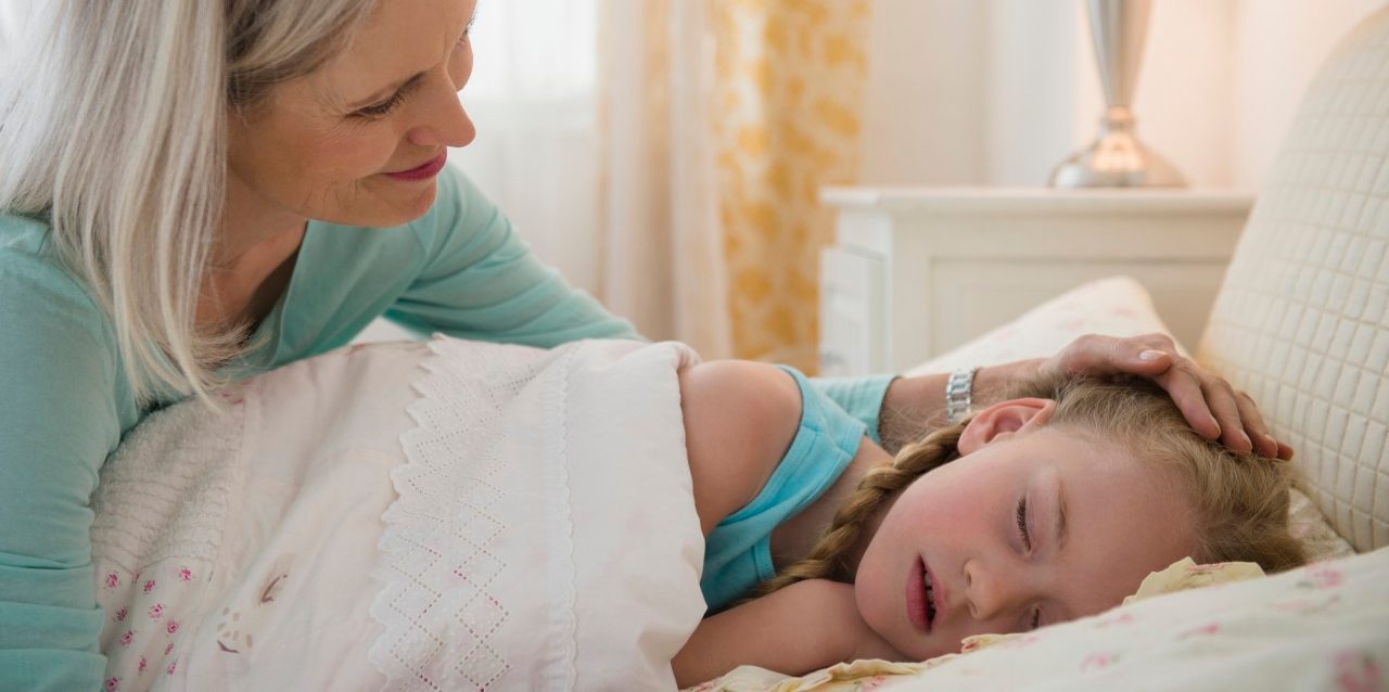 31 Jan 2014 --- Senior Caucasian woman putting granddaughter to bed --- Image by © JGI/Jamie Grill/Blend Images/Corbis