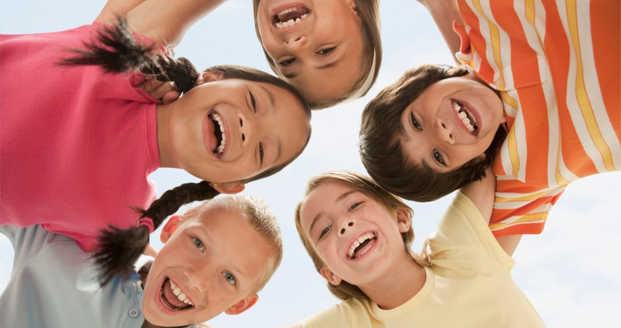 West New York, New Jersey, USA --- Smiling children huddling together --- Image by © KidStock/Blend Images/Corbis