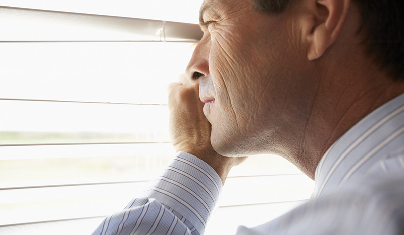 Man Peeking Through Venetian Blinds --- Image by © Tim Pannell/Corbis