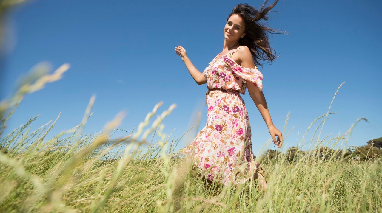 Young woman walking in field with arms raised --- Image by © Tomas Rodriguez/Corbis