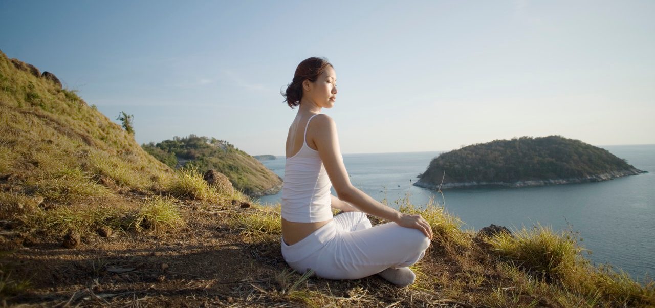 Thailand --- Young Woman Meditating on a Hill --- Image by © Ken Seet/Corbis