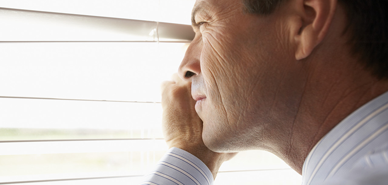 Man Peeking Through Venetian Blinds --- Image by © Tim Pannell/Corbis