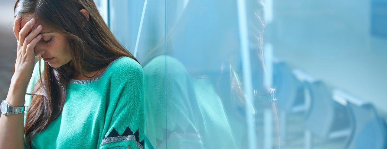 25 Apr 2014 --- Mid adult businesswoman leaning against glass wall in office with hand on face --- Image by © Ghislain & Marie David de Lossy/Corbis