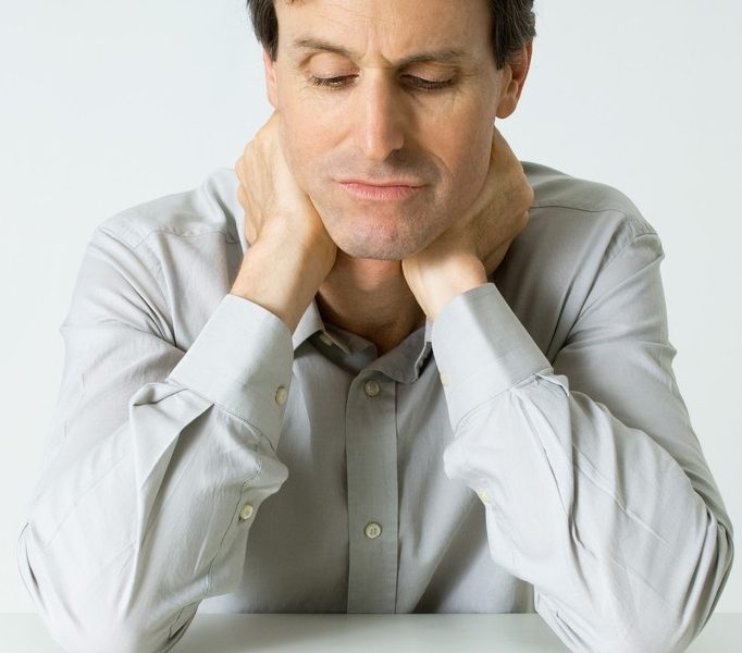 Man Sitting Next To Pills, Holding Neck, Looking Down --- Image by © Michele Constantini/PhotoAlto/Corbis