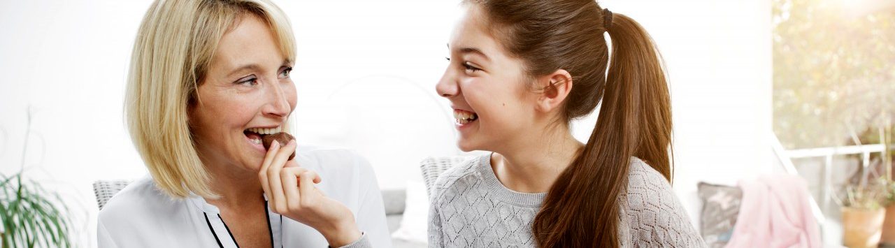 09 Nov 2014 --- Mother and daughter eating cookies, watching digital tablet --- Image by © Gabi Dilly/Westend61/Corbis