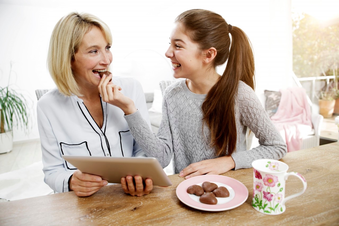 09 Nov 2014 --- Mother and daughter eating cookies, watching digital tablet --- Image by © Gabi Dilly/Westend61/Corbis