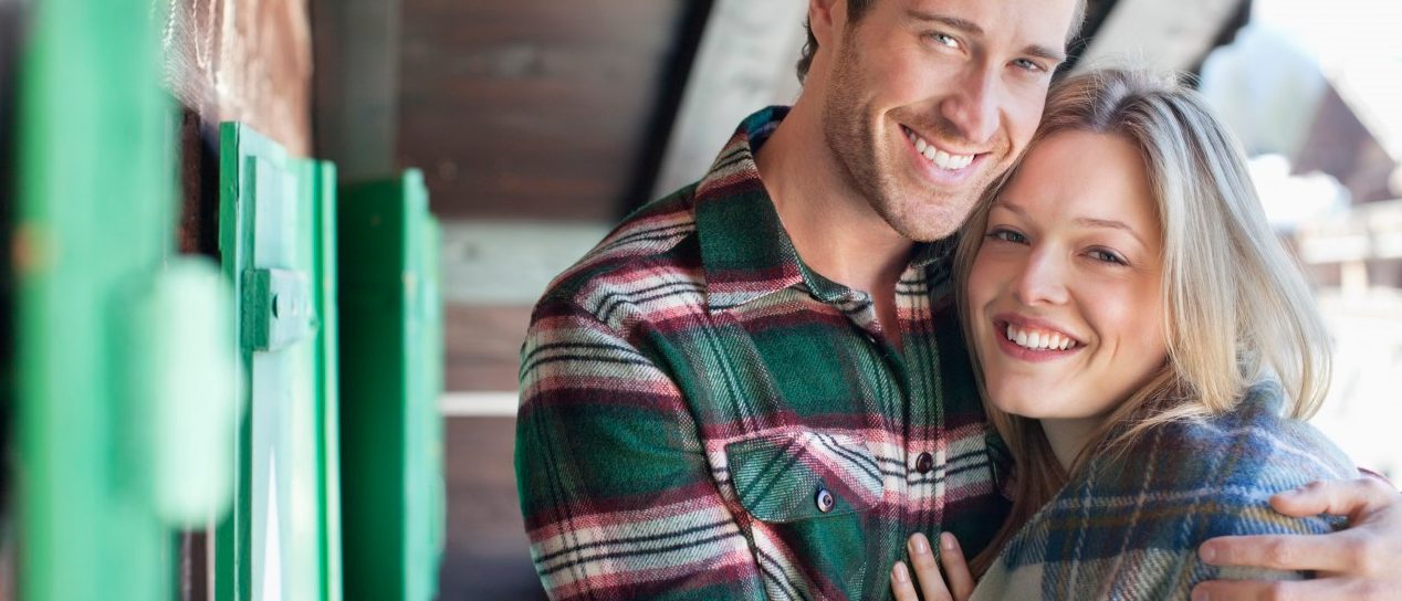 Switzerland, Switzerland --- Portrait of smiling couple hugging on cabin porch --- Image by © 237/Sam Edwards/Ocean/Corbis