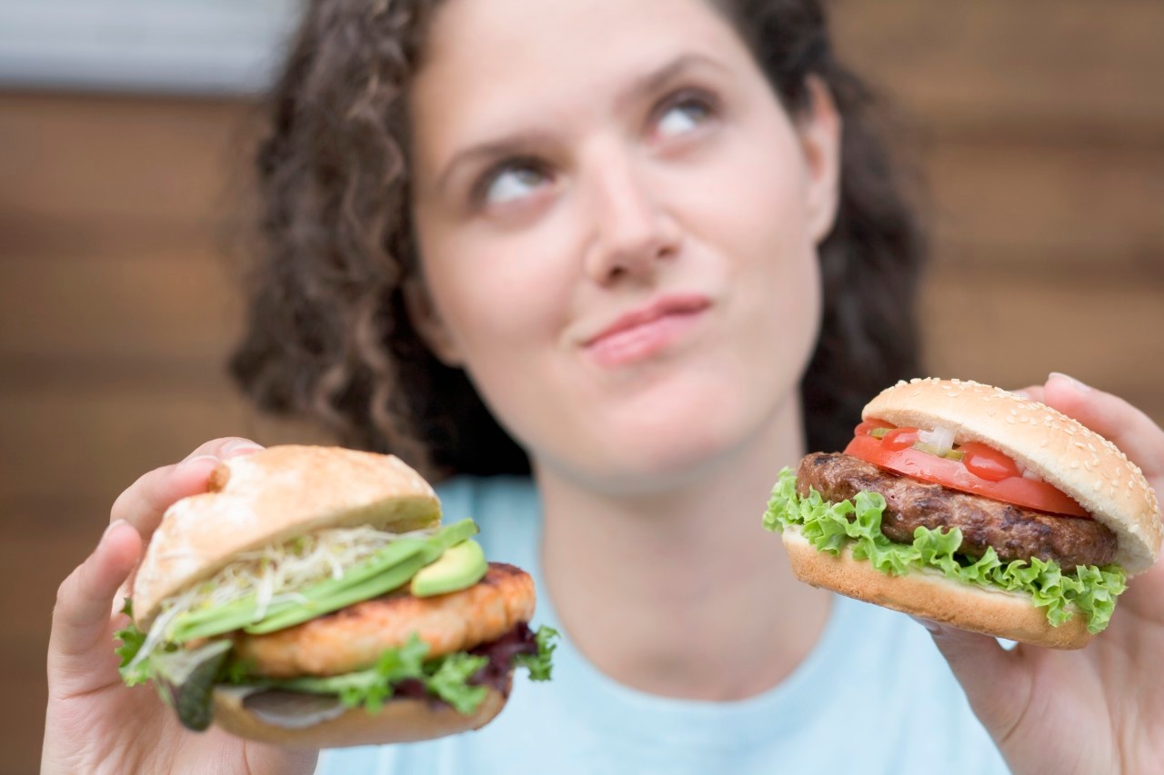 28 Feb 2008 --- Woman with two different burgers --- Image by © the food passionates/Corbis