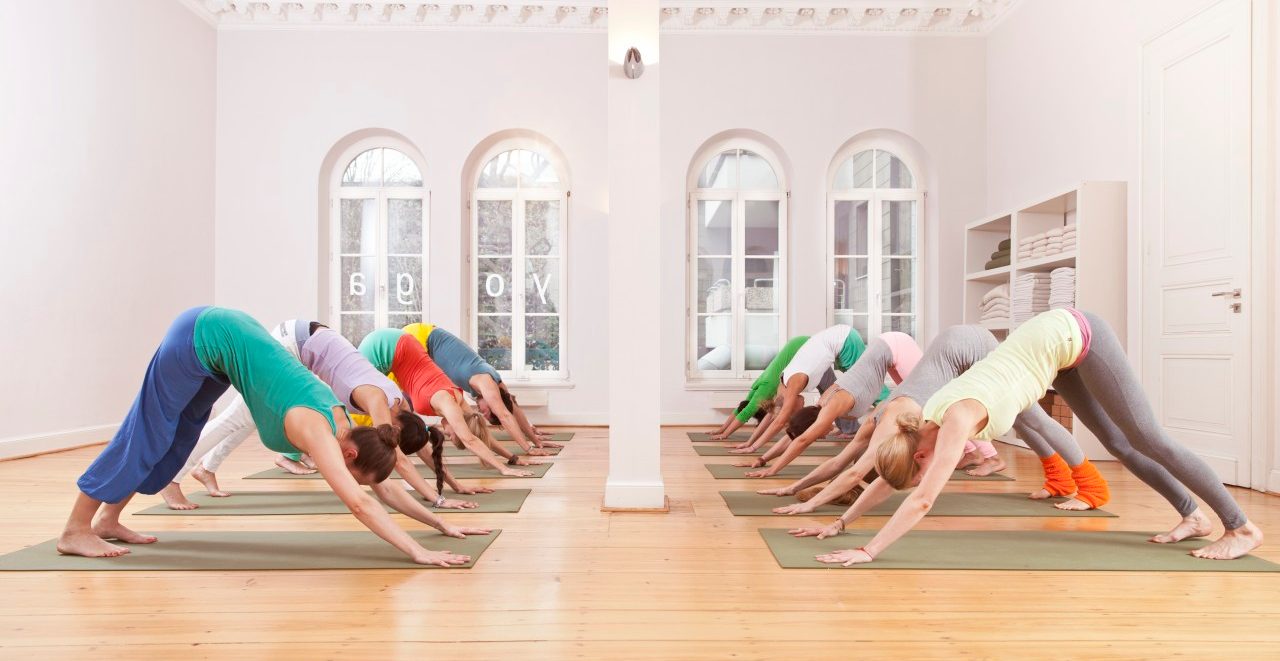 Group of mid adult women and mid adult man doing downward-facing dog pose in yoga studio --- Image by © Mareen Fischinger/Corbis