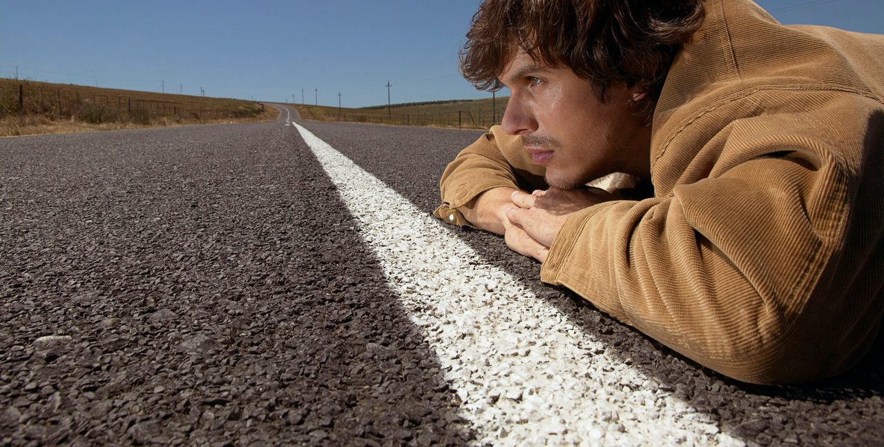 A man lies down in the middle of the road --- Image by © Ansgar Photography/Corbis