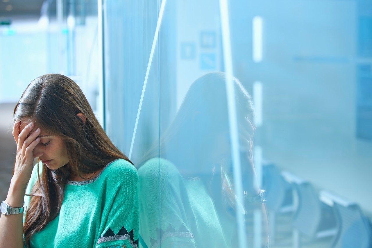 25 Apr 2014 --- Mid adult businesswoman leaning against glass wall in office with hand on face --- Image by © Ghislain & Marie David de Lossy/Corbis