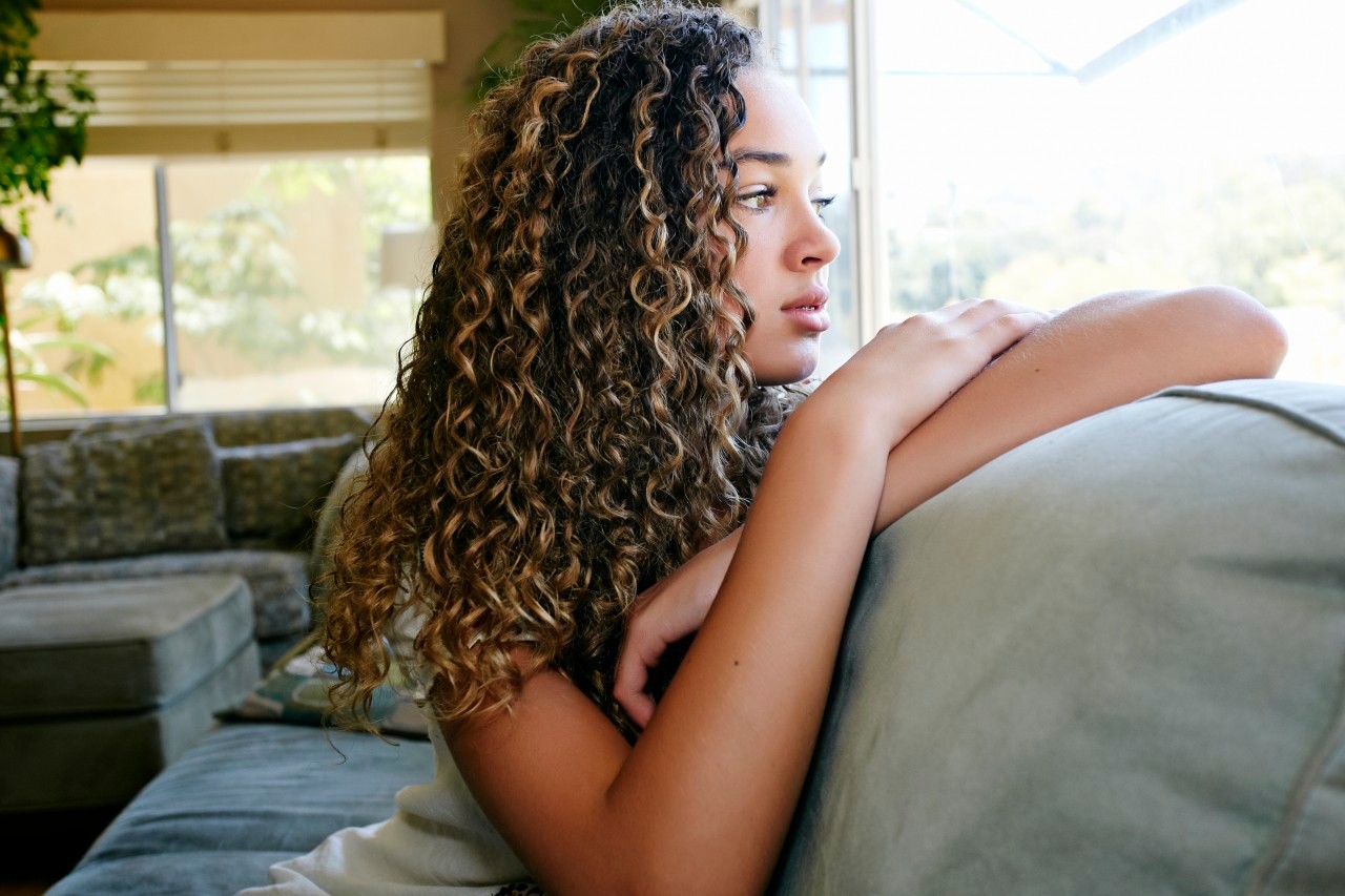 21 Aug 2013 --- Mixed race girl sitting on sofa --- Image by © Peathegee Inc/Blend Images/Corbis