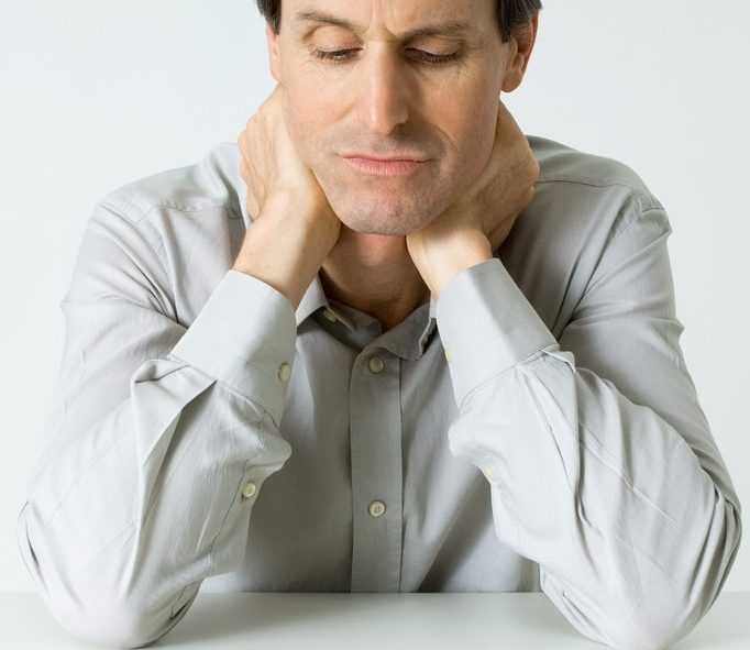 Man Sitting Next To Pills, Holding Neck, Looking Down --- Image by © Michele Constantini/PhotoAlto/Corbis