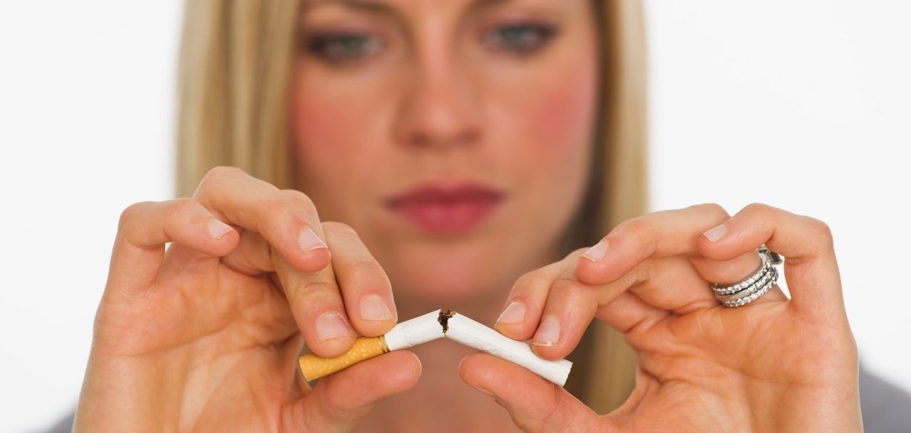 Young woman breaking cigarette --- Image by © Tetra Images/Corbis