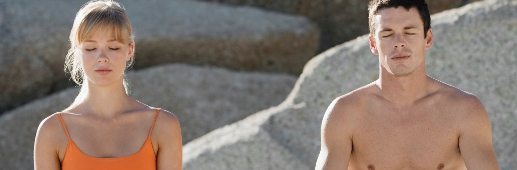 Couple meditating on beach --- Image by Â© Corbis