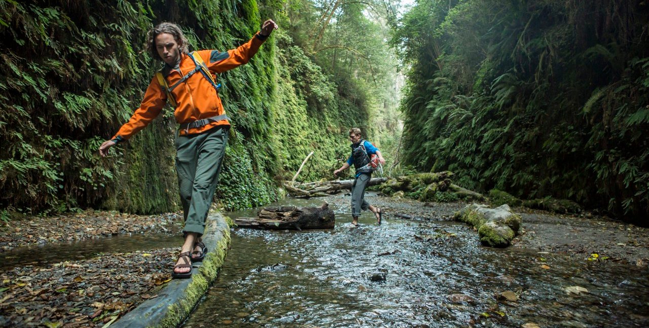 Hiker balancing on logs in forest --- Image by © Jordan Siemens/Corbis