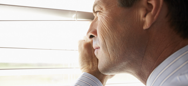 Man Peeking Through Venetian Blinds --- Image by © Tim Pannell/Corbis