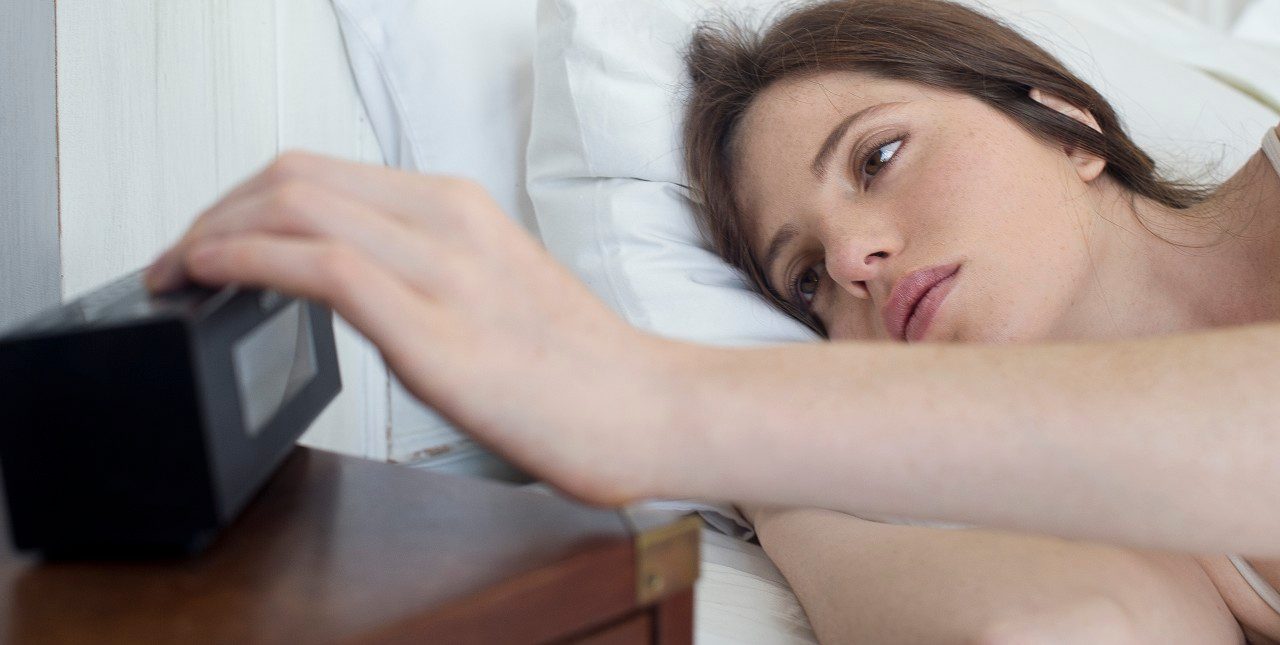 18 Feb 2014 --- Woman in bed pressing alarm clock snooze button --- Image by © Frederic Cirou/PhotoAlto/Corbis