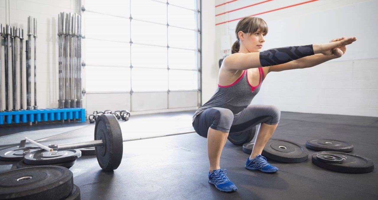 20 Nov 2013, Calgary, Alberta, Canada --- Woman warming up with squats in gym --- Image by © Hero Images/Corbis