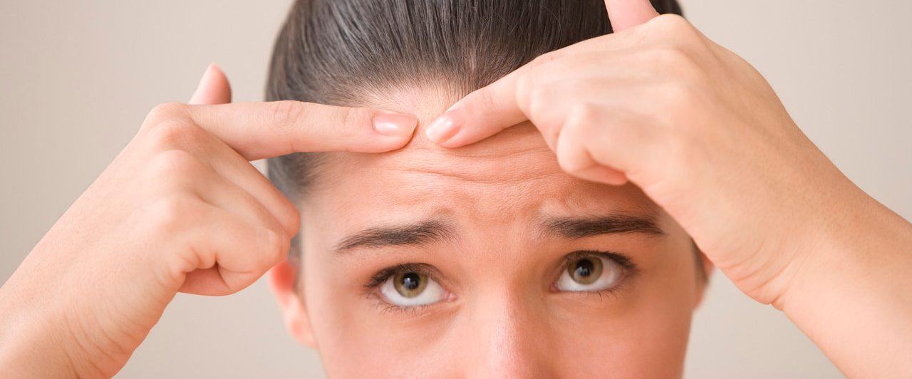 Close up of teenage girl popping pimple --- Image by © Jose Luis Pelaez, Inc./Blend Images/Corbis