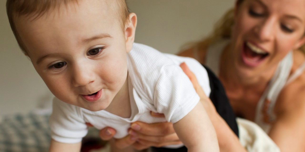 14 Apr 2014 --- Mother guiding baby boy crawling on bed --- Image by © Christine Schneider/Corbis