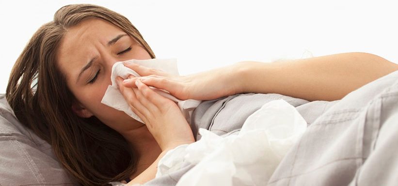 Young woman lying in bed blowing nose --- Image by Â© Mike Kemp/Tetra Images/Corbis