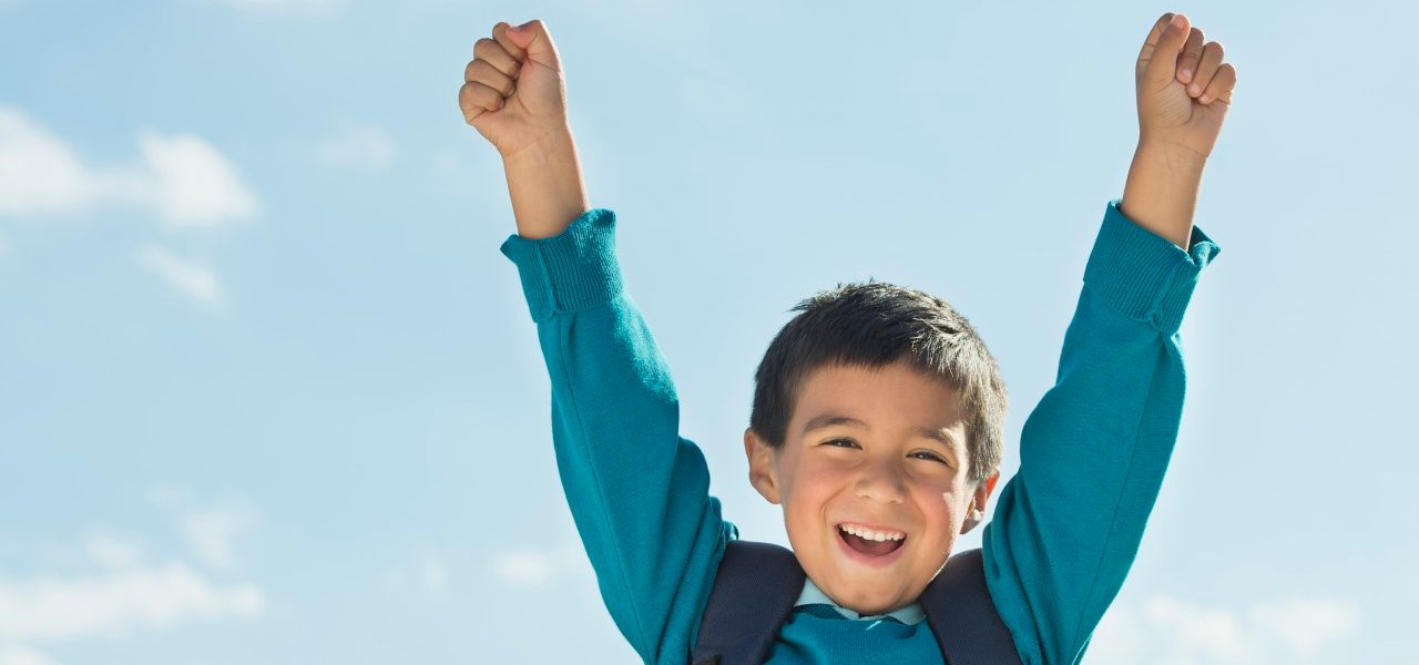 Boy (6-7) wearing backpack punching air --- Image by © Tetra Images/Corbis