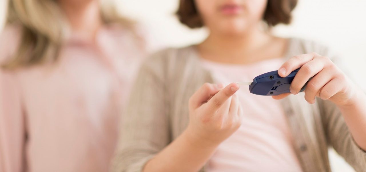 Hispanic girl testing her blood sugar --- Image by © JGI/Tom Grill/Blend Images/Corbis