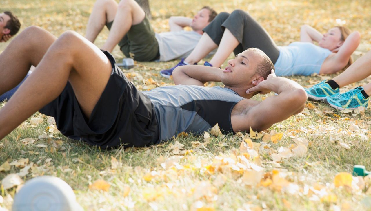 19 Sep 2012 --- Bootcamp class doing sit-ups outdoors. --- Image by © Hero Images/Corbis