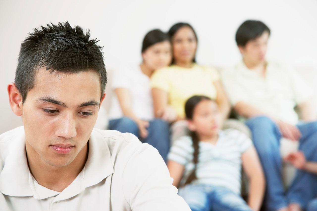 Teen boy with family in background --- Image by © Tomas Rodriguez/Corbis