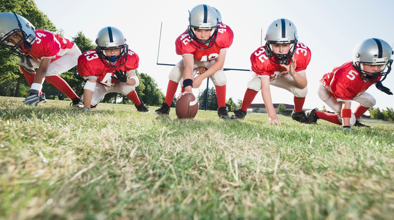 Football players at line of scrimmage ready to snap football --- Image by © Erik Isakson/Tetra Images/Corbis