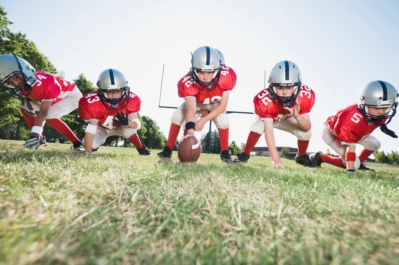 Football players at line of scrimmage ready to snap football --- Image by © Erik Isakson/Tetra Images/Corbis