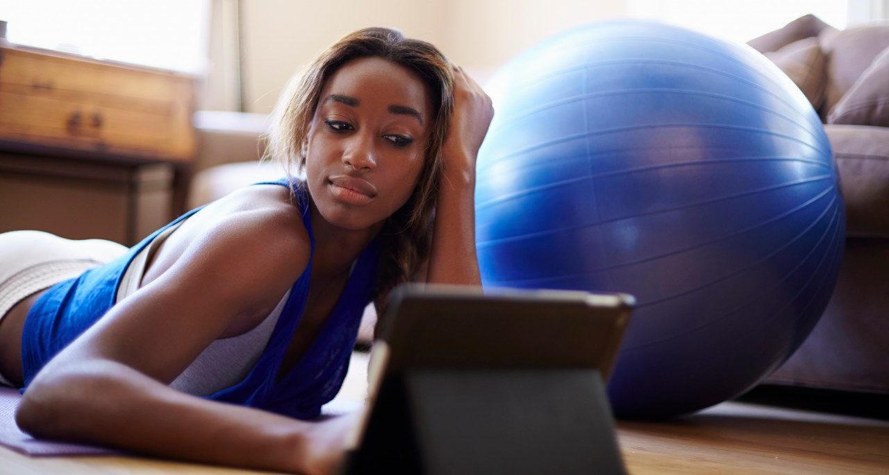 27 Jun 2014 --- Young woman taking a training break, using digital tablet in sitting room --- Image by © Kevin Kozicki/Image Source/Corbis