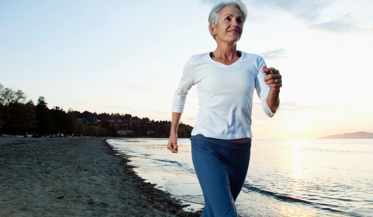 Woman running on beach --- Image by © Monalyn Gracia/Corbis