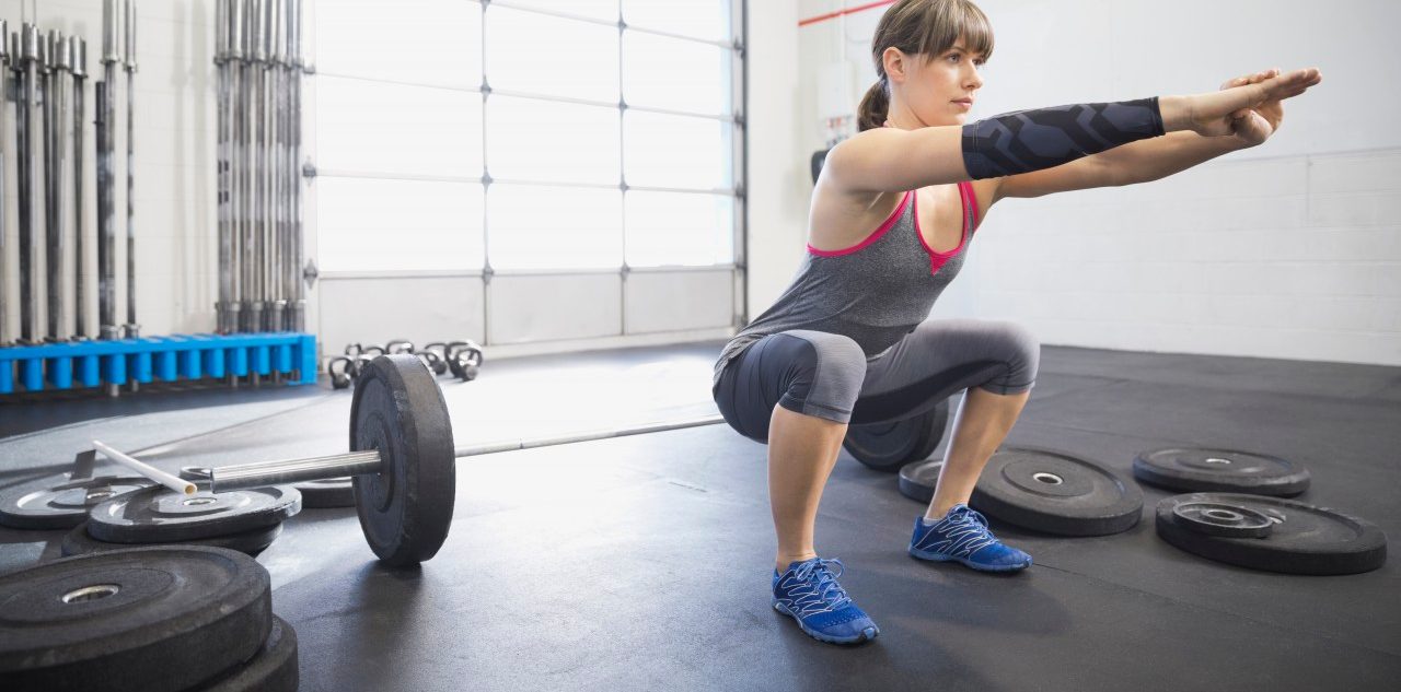 20 Nov 2013, Calgary, Alberta, Canada --- Woman warming up with squats in gym --- Image by © Hero Images/Corbis