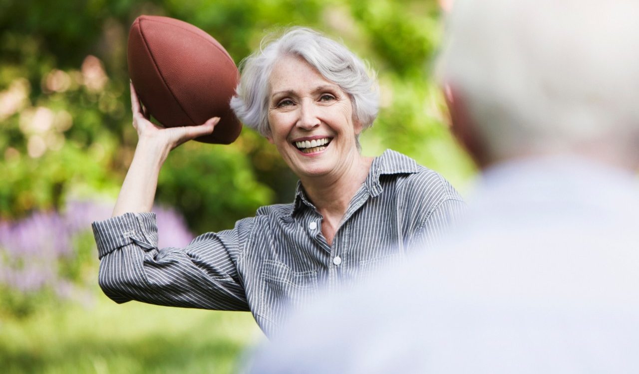 Senior woman throwing football to partner --- Image by © JOSE LUIS PELAEZ, INC./Image Source/Corbis