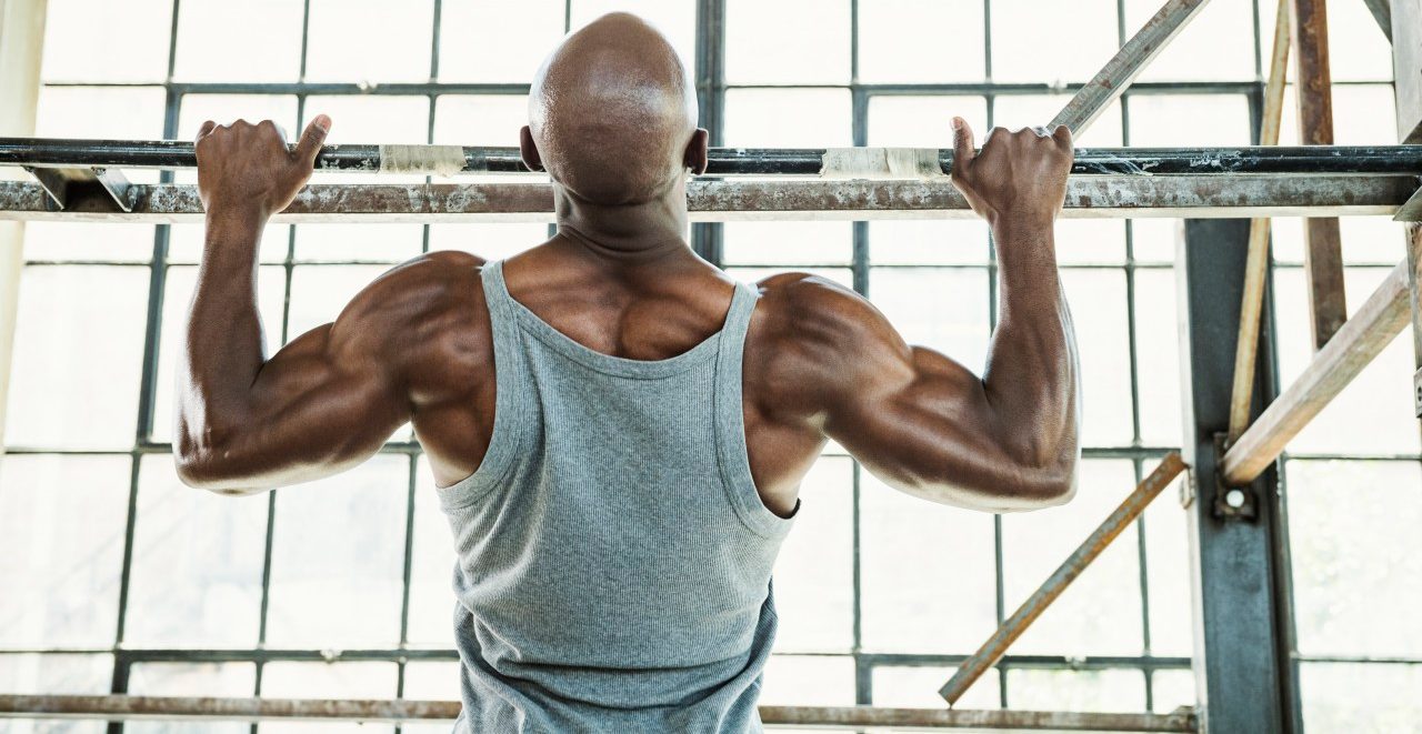 06 Aug 2014 --- Black man doing pull-ups in warehouse --- Image by © Erik Isakson/Blend Images/Corbis