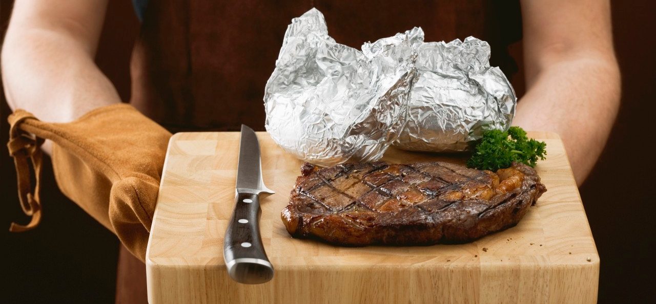 02 May 2007 --- Man holding grilled beef steak on chopping board --- Image by © the food passionates/Corbis