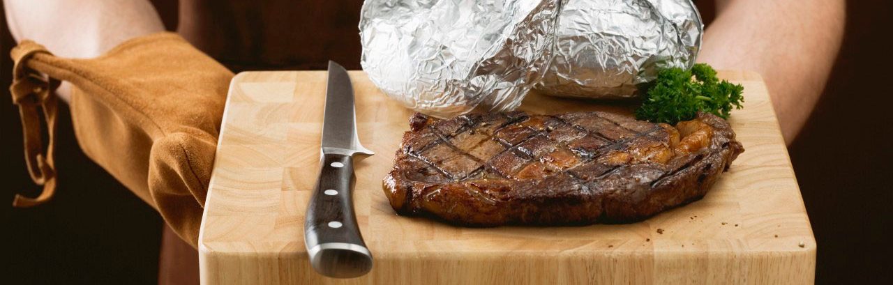 02 May 2007 --- Man holding grilled beef steak on chopping board --- Image by Â© the food passionates/Corbis