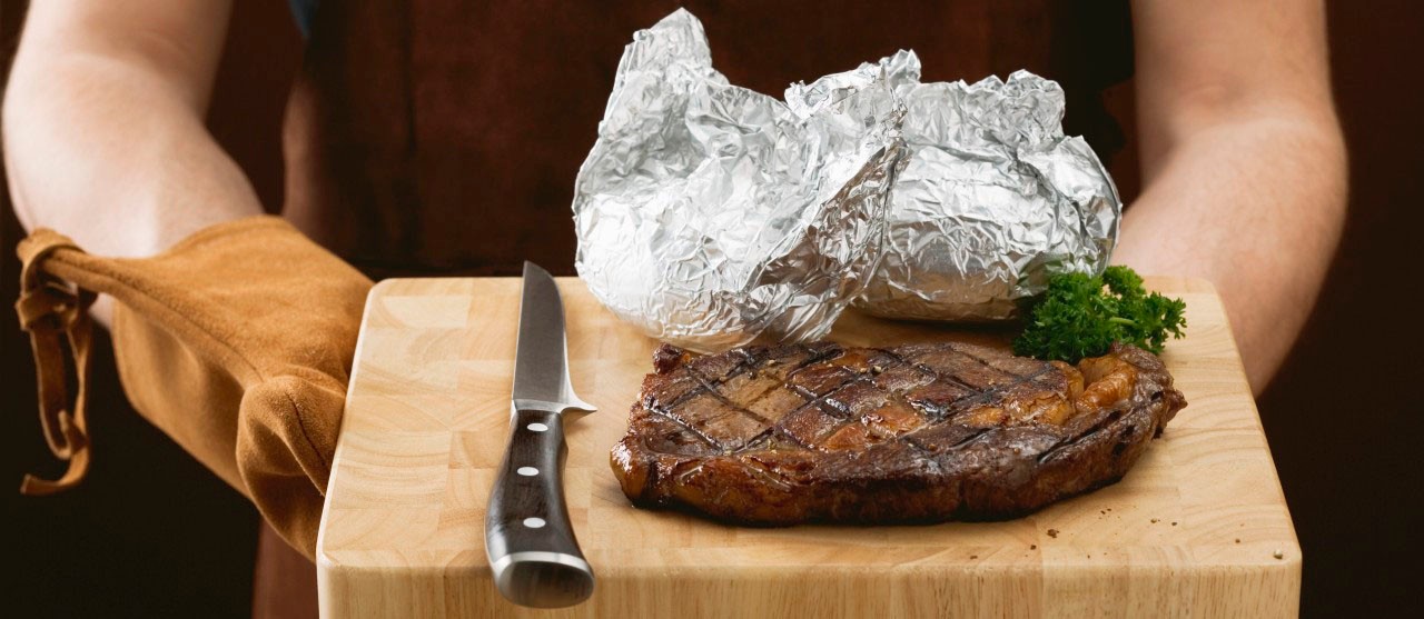 02 May 2007 --- Man holding grilled beef steak on chopping board --- Image by Â© the food passionates/Corbis