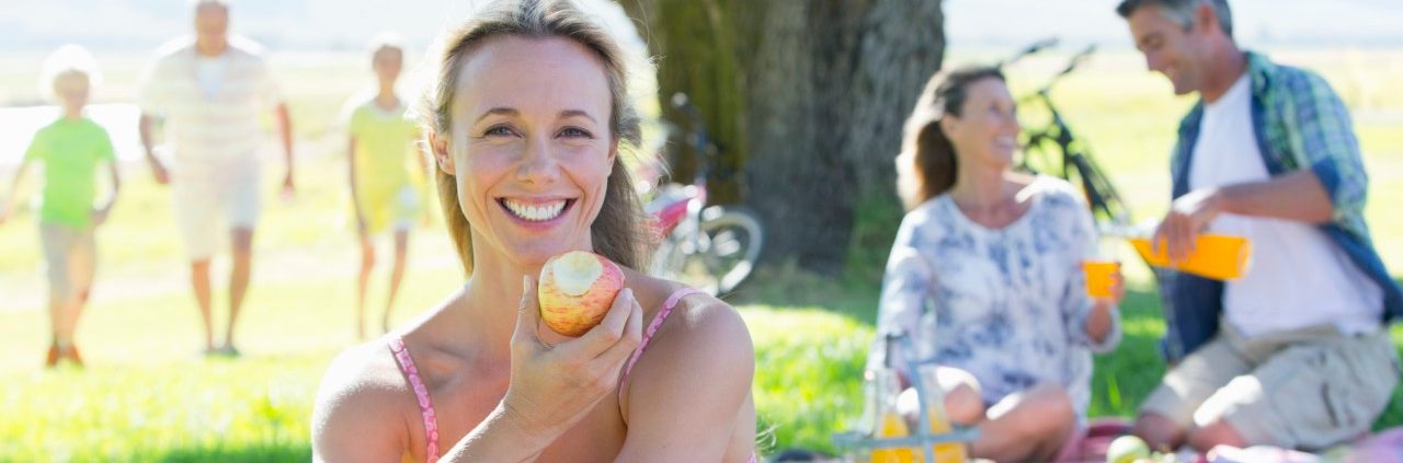 17 Nov 2014, Cape Town, South Africa --- Woman eating apple with Multi generation family having a picnic in countryside --- Image by © Graham Oliver/Juice Images/Corbis