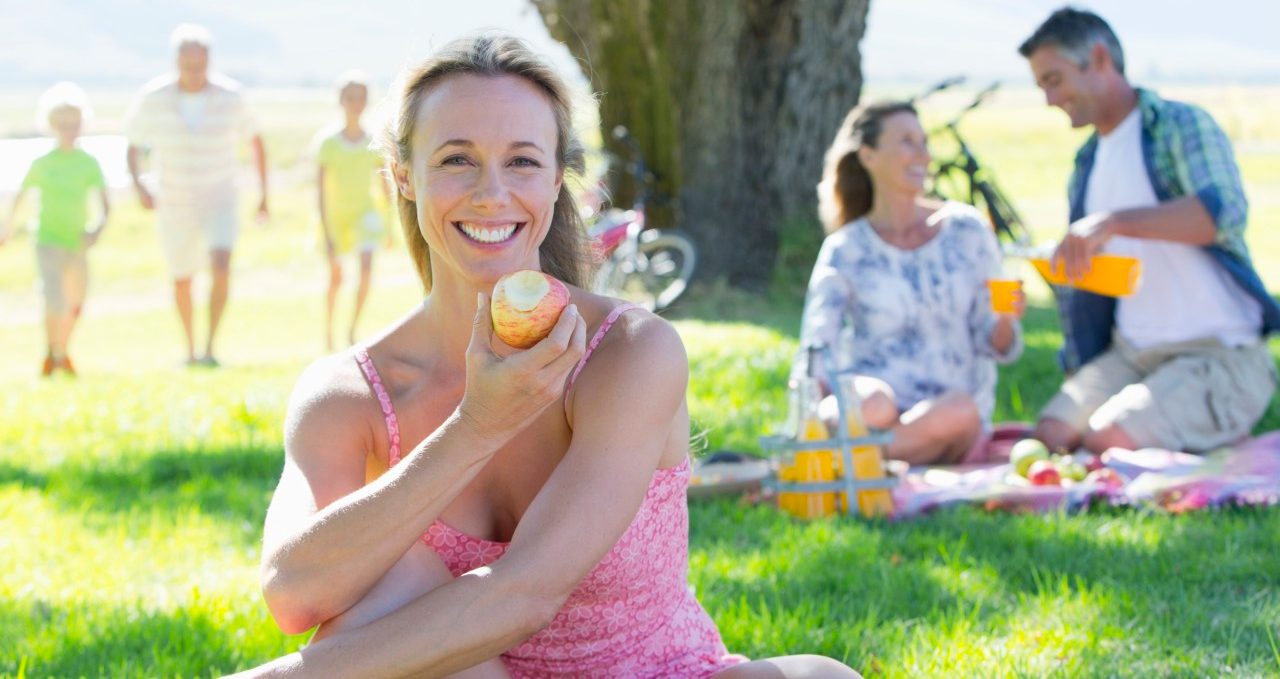 17 Nov 2014, Cape Town, South Africa --- Woman eating apple with Multi generation family having a picnic in countryside --- Image by © Graham Oliver/Juice Images/Corbis