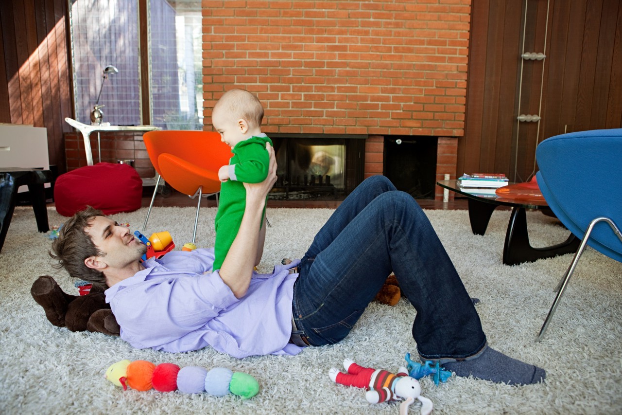 Father playing with baby son in living room --- Image by © Image Source/Corbis