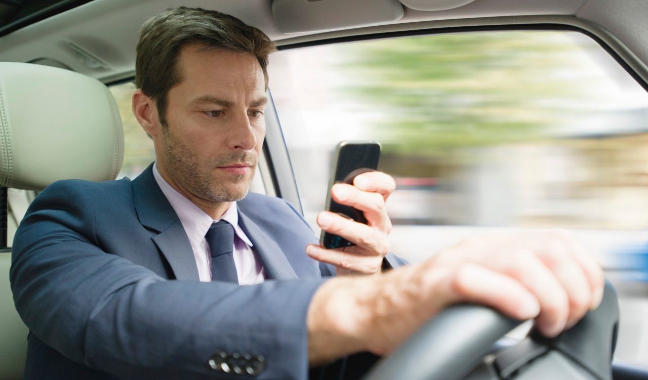 18 Jul 2013 --- Businessman looking at smartphone in car --- Image by © Frederic Cirou/PhotoAlto/Corbis